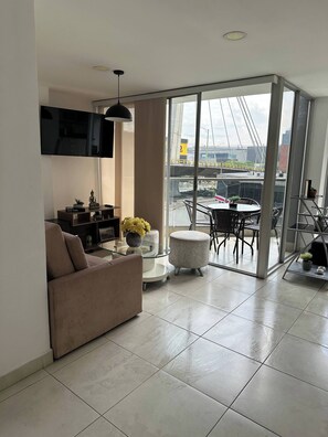 Una sala de estar moderna con un sofá, una mesa de centro de vidrio y un televisor montado en la pared.