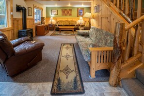 A cozy living room with a fireplace, leather sofa, and a wooden staircase.