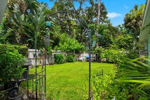A well-maintained backyard with a grassy lawn, a wooden fence, and various plants and trees. - 7 Mi to Historic Dtwn! New Port Richey Cottage (New Port Richey)