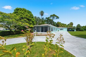 A two-story building with a covered porch and a clear sky. - Relax on the Grand River! Bright Waterfront Home (New Port Richey)