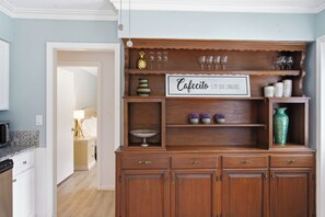 A kitchen with wooden cabinets, a coffee station, and a sign that says 'Cafecito is my love language.' - Relax on the Grand River! Bright Waterfront Home (New Port Richey)