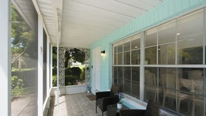 Eine überdachte Veranda mit Korbmöbeln und einem großen Fenster.