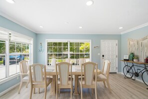 A dining room with a table and chairs, large windows, and a door. - Relax on the Grand River! Bright Waterfront Home (New Port Richey)