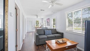 A modern living room with a gray sofa, a wooden coffee table, and a ceiling fan. - Newly Remodeled Home 1 Mi to Dtwn New Port Richey (New Port Richey)