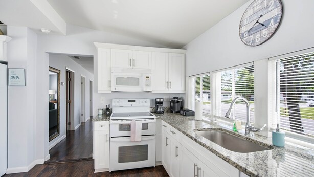 A modern kitchen with white cabinetry, a built-in microwave, a stove, and a sink. - Newly Remodeled Home 1 Mi to Dtwn New Port Richey (New Port Richey)