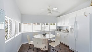 A kitchen with a round dining table, white chairs, a ceiling fan, and white cabinetry. - Newly Remodeled Home 1 Mi to Dtwn New Port Richey (New Port Richey)