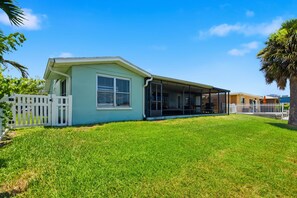 A single-story house with a covered porch, a fenced yard, and a clear blue sky.