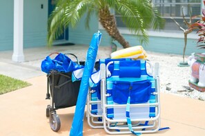 A luggage cart with a blue suitcase and a blue duffel bag, a black bag, and a yellow and white beach towel.