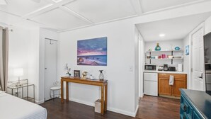 A compact hotel room with a bed, a bedside table, a desk, a chair, a painting, a kitchenette, and a bathroom. - Updated Studio 1 Mi to Dtwn NPR & Cotee River! (New Port Richey)