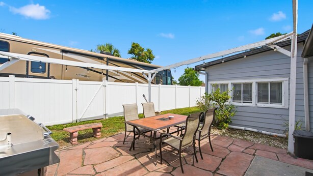 A patio with a table and chairs, a barbecue grill, and a covered area with a vehicle. - Updated Studio 1 Mi to Dtwn NPR & Cotee River! (New Port Richey)