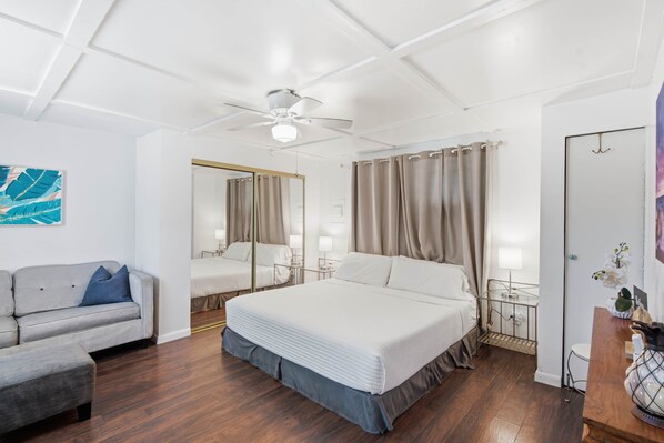 Ein Hotelzimmer mit einem großen Bett, einer Couch, einem Deckenventilator und einem Spiegel.
