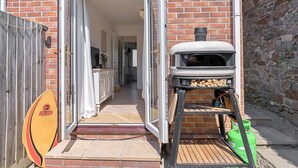 Un bâtiment en briques doté d’une terrasse en bois, d’un barbecue et d’une planche de surf.