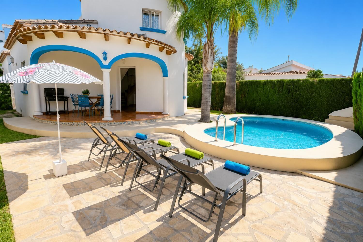 A poolside area with lounge chairs, a pool, and a patio with a table and chairs.