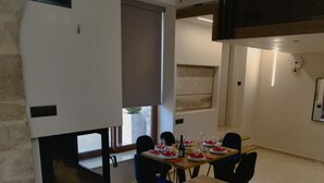 Uma área de refeições com uma mesa posta para quatro, cadeiras e uma janela com persianas.