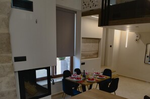 Ein Essbereich mit Tisch, vier Stühlen und einem Fenster mit Jalousien.