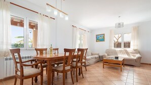 Ett rymligt vardagsrum med ett matbord, stolar, en soffa och ett soffbord.