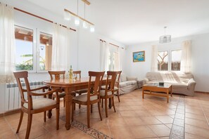 Ein geräumiger Wohnbereich mit Esstisch, Stühlen, einer Couch und einem Couchtisch.