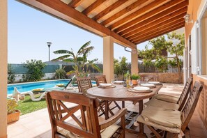 An outdoor patio with a pool, wooden furniture, and a view of the surrounding landscape. - Villa Tintoretto - Four Bedroom Villa, Sleeps 8 (Mallorca)