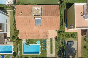Terraço no topo com piscina, espreguiçadeiras e um pequeno jardim.