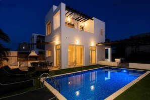 Une maison moderne à deux étages dotée d’une piscine, d’un espace salon extérieur et d’une pergola.