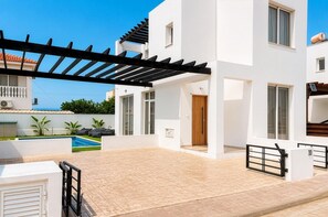 Un immeuble résidentiel moderne à deux étages, doté d’un patio couvert, d’une piscine et d’un petit jardin.