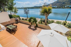 A patio with a dining table and chairs, a barbecue grill, and umbrellas. - Villa Isleta - Four Bedroom Villa, Sleeps 8 (Mallorca)