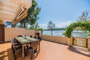 An outdoor patio with a table set for dining, a grill, and a view of a lake. - Villa Isleta - Four Bedroom Villa, Sleeps 8 (Mallorca)