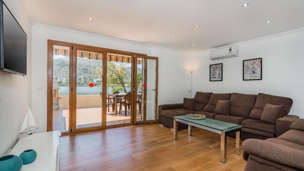Ein Wohnzimmer mit einer Couch, einem Couchtisch und einem an der Wand befestigten Fernseher.