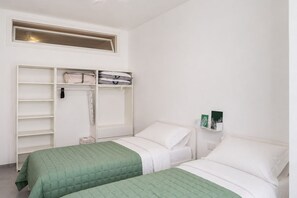 A bedroom with two beds, a wardrobe, and a shelf with books. - GuestHost - Comfy Verandah Flat X6 Near the Sea (Trani)
