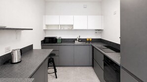 A modern kitchen with grey cabinets, a black countertop, a kettle, a toaster, and a sink. - GuestHost - Comfy Verandah Flat X6 Near the Sea (Trani)