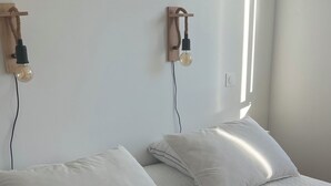 Ein Schlafzimmer mit zwei Betten, jeweils mit weißer Bettwäsche und Kissen, sowie einer an der Wand befestigten Holzleuchte.
