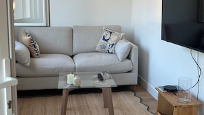 Ein Wohnzimmer mit einer Couch, einem Couchtisch, einem Fernseher und einem kleinen Holztisch.