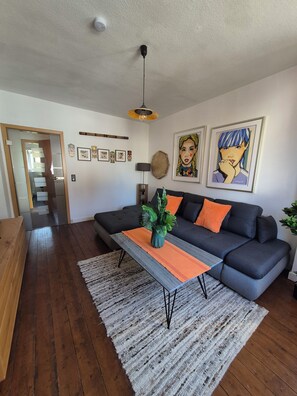 Ein modernes Wohnzimmer mit einem grauen Sofa, einem Holztisch und einem grauen Teppich.