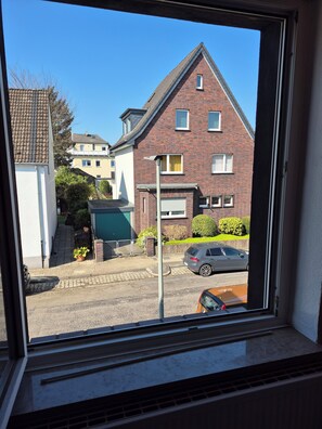 Eine Wohnstraße mit Häusern, einem geparkten Auto und blauem Himmel.