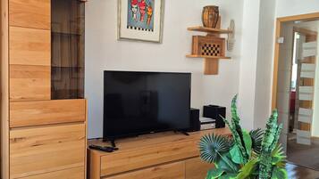 Ein modernes Wohnzimmer mit einer Holz-Unterhaltungsecke, einem Flachbildfernseher, einem gerahmten Kunstwerk und einem Blumentopf.