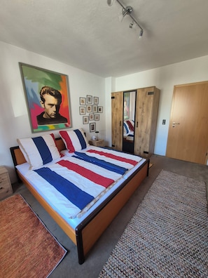 A bedroom with a bed, a wardrobe, a mirror, and a painting on the wall. - Tranquil 1-bedroom apartment in Oberhausen for a relaxing stay (Oberhausen)