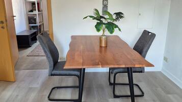 Ein Essbereich mit Holztisch, schwarzen Metallstühlen, einem Blumentopf und verschiedenen Wanddekorationen, darunter Uhren und Schilder.