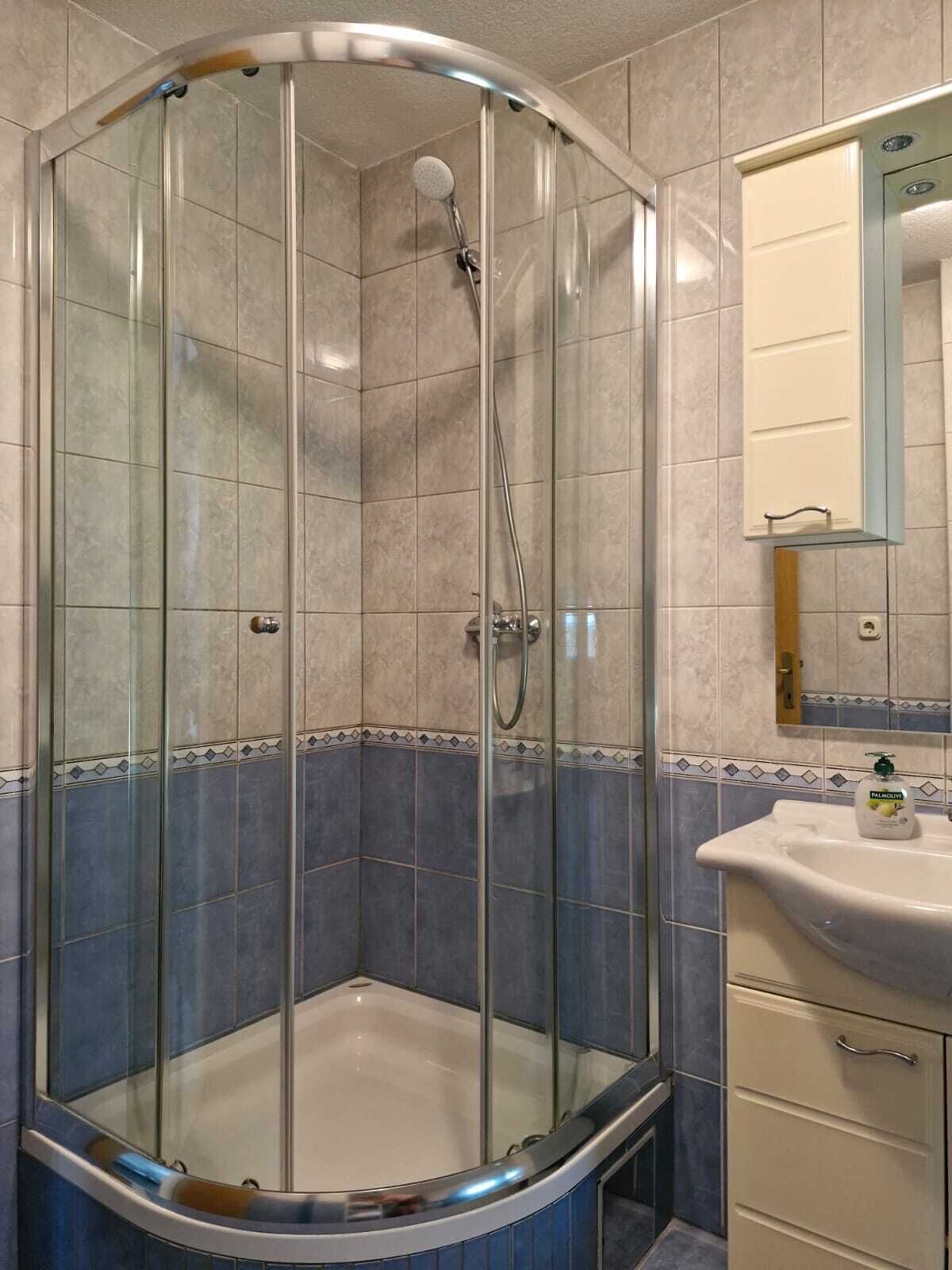 Eine begehbare Dusche mit Glaswänden, einer Duschbrause und einem Handbrausehalter.