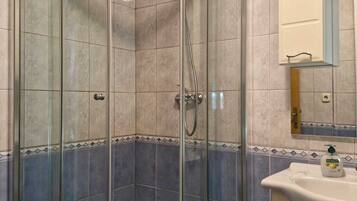 Eine begehbare Dusche mit Glaswänden, einer Duschbrause und einem Handbrausehalter.