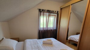 A bedroom with two beds, a window with curtains, and a wooden wardrobe. - Duvnjak Rooms (Livno)