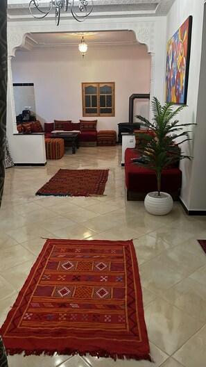A living room with a sofa set, a coffee table, a fireplace, a potted plant, and a large rug.