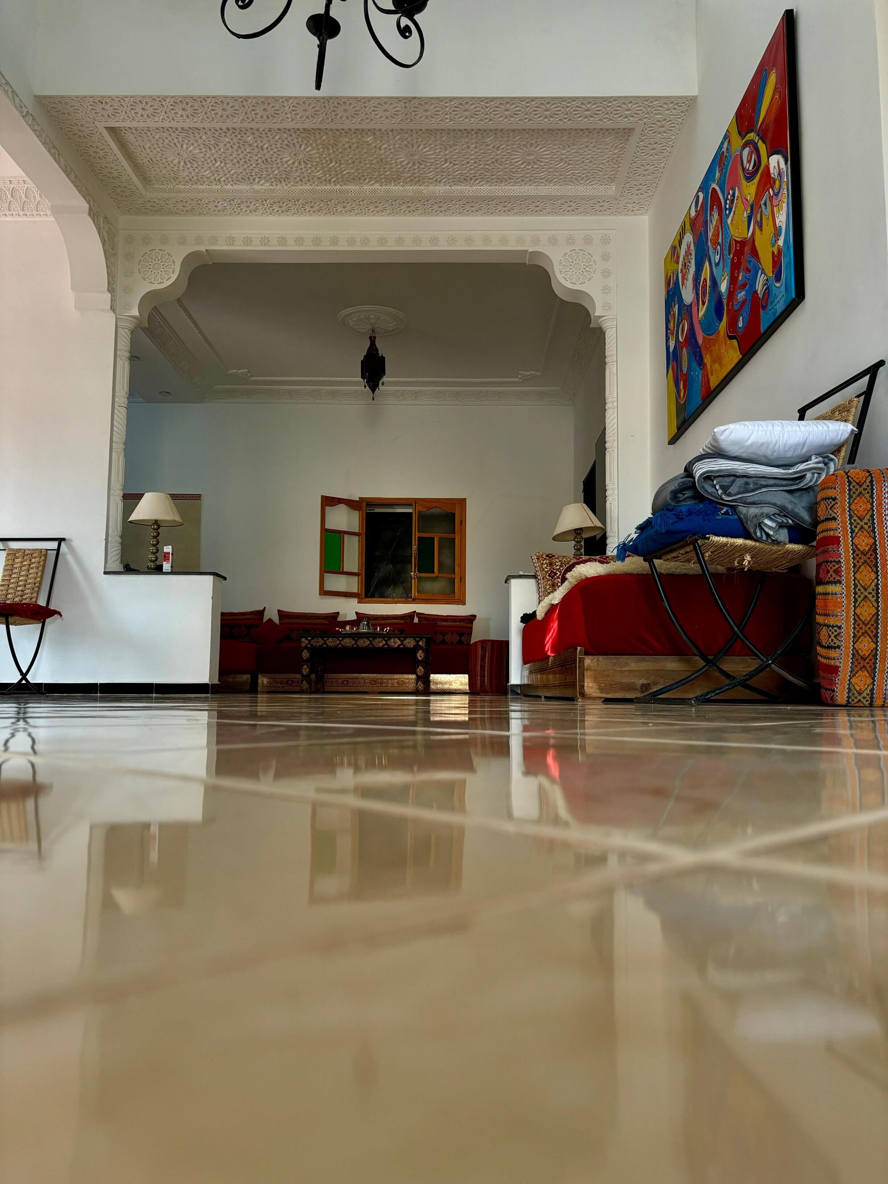 A spacious living room with a polished floor, a sofa set, a coffee table, and a painting on the wall.