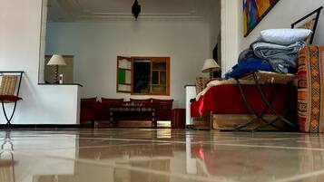 A spacious living room with a polished floor, a sofa set, a coffee table, and a painting on the wall.