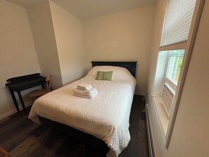 Une chambre à coucher avec un lit, une chaise, un bureau et une fenêtre.