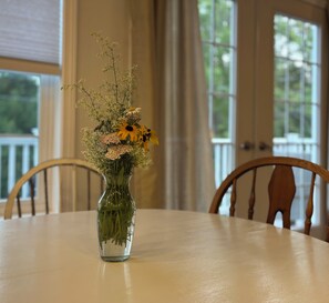 Een helder uitzicht op een eettafel met een bloevas in het midden.