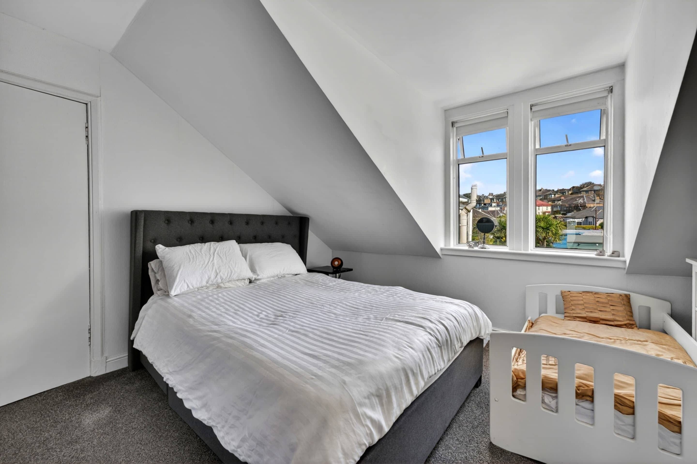 Ein Schlafzimmer mit Bett, Fenster und Blick ins Freie.