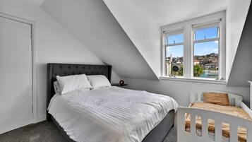 Ein Schlafzimmer mit Bett, Fenster und Blick ins Freie.