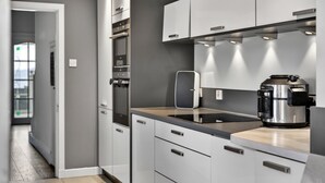 Eine moderne Küche mit grauen Schränken, einer schwarzen Arbeitsplatte und einer Kaffeemaschine.