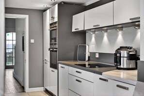 A modern kitchen with grey cabinets, a black countertop, and a coffee maker. - Charming Devon Cottage With Garden (West Kilbride)