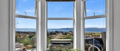 A bay window with a view of a coastal town and the sea.